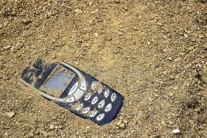 teléfono-móvil-enterrado-en-la-arena-gris-137171592