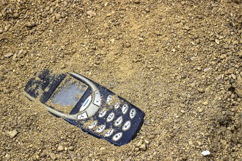 teléfono-móvil-enterrado-en-la-arena-gris-137171592